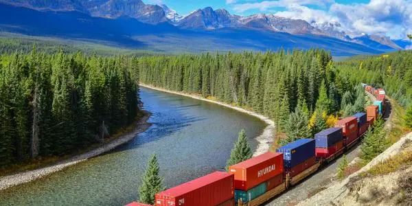 A train traveling through the mountains near water.
